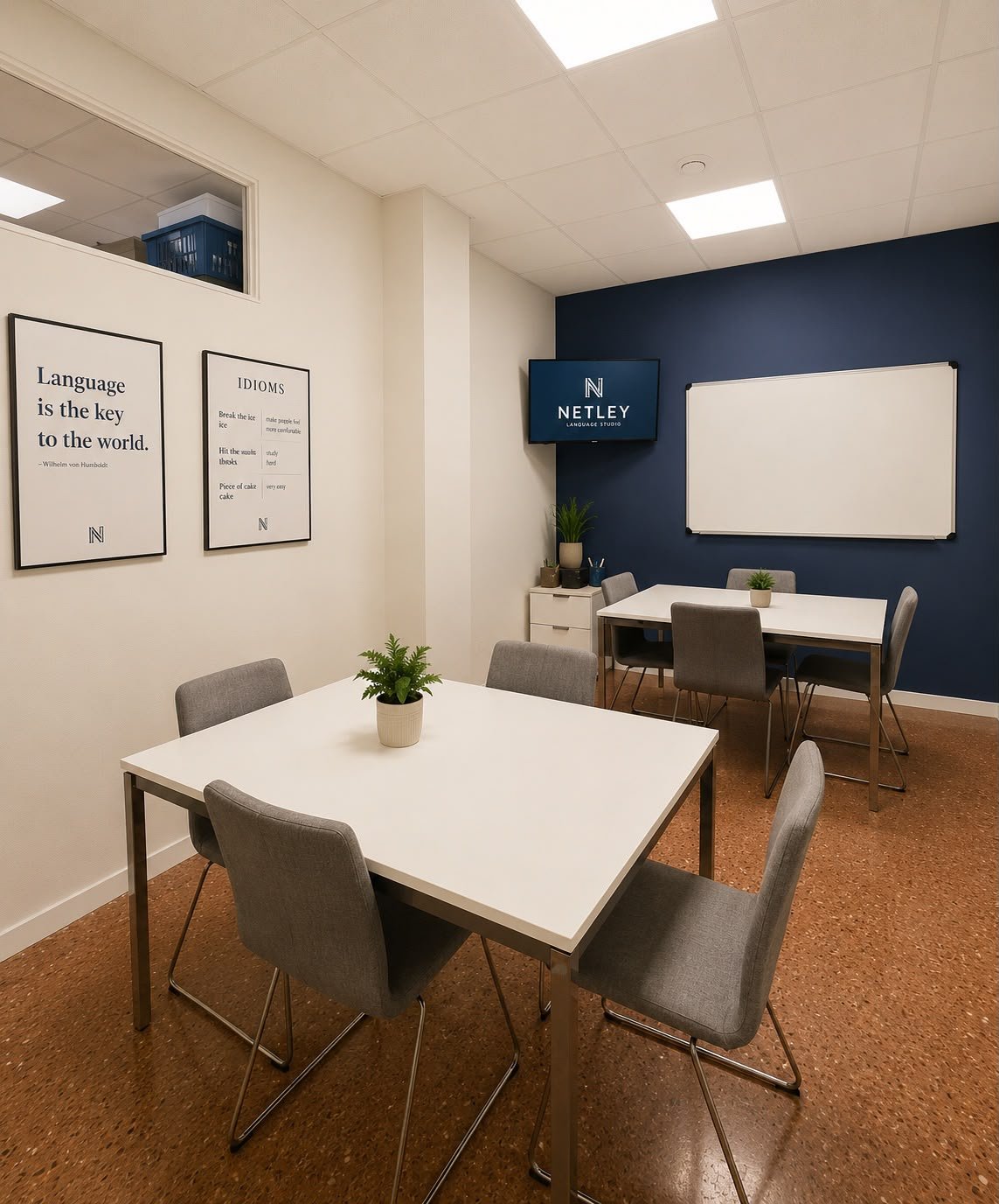Aula de Netley Language Studio con mesas, pizarra blanca, pantalla con el logo Netley y carteles con la frase «Language is the key to the world».